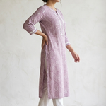 A woman standing sideways wearing a purple printed straight kurta and white pants, showcasing the garment fit.
