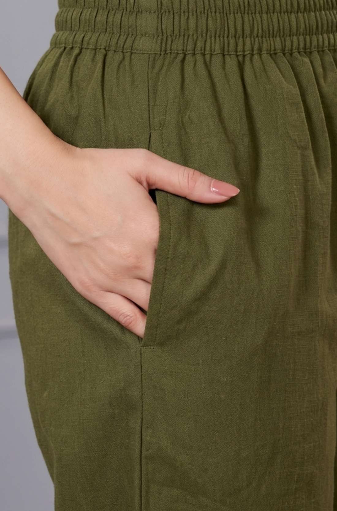 Close up view showcasing the practical side utility pocket seamlessly tailored into a sage green cotton floral print straight kurta, with a hand resting inside the pocket over matching straight trousers.