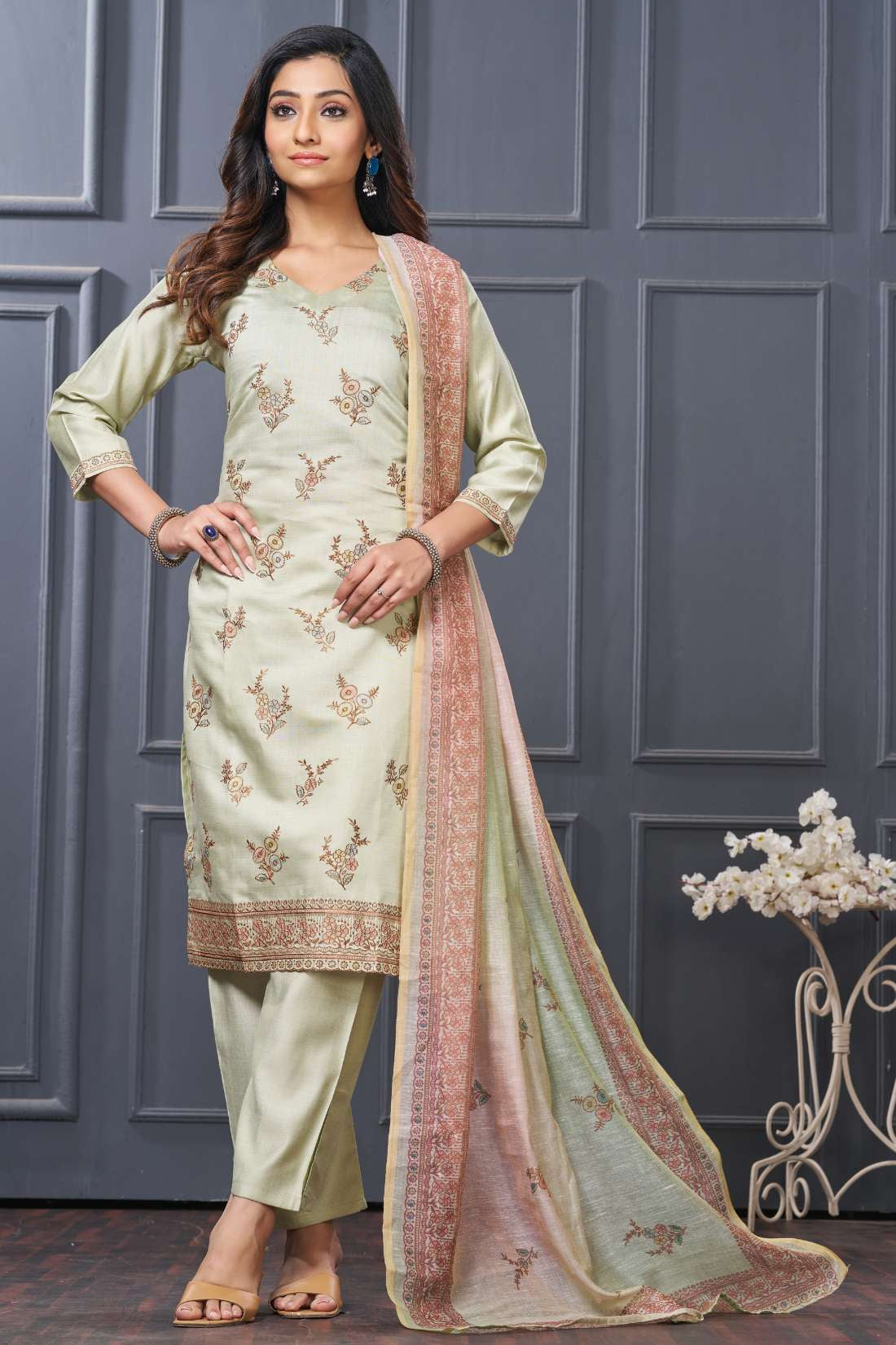 Front full-length view of a model showcasing the mint green silk 3-piece variant, featuring delicate gold embroidery details on the neckline, paired with straight trousers and a matching green scalloped border dupatta.