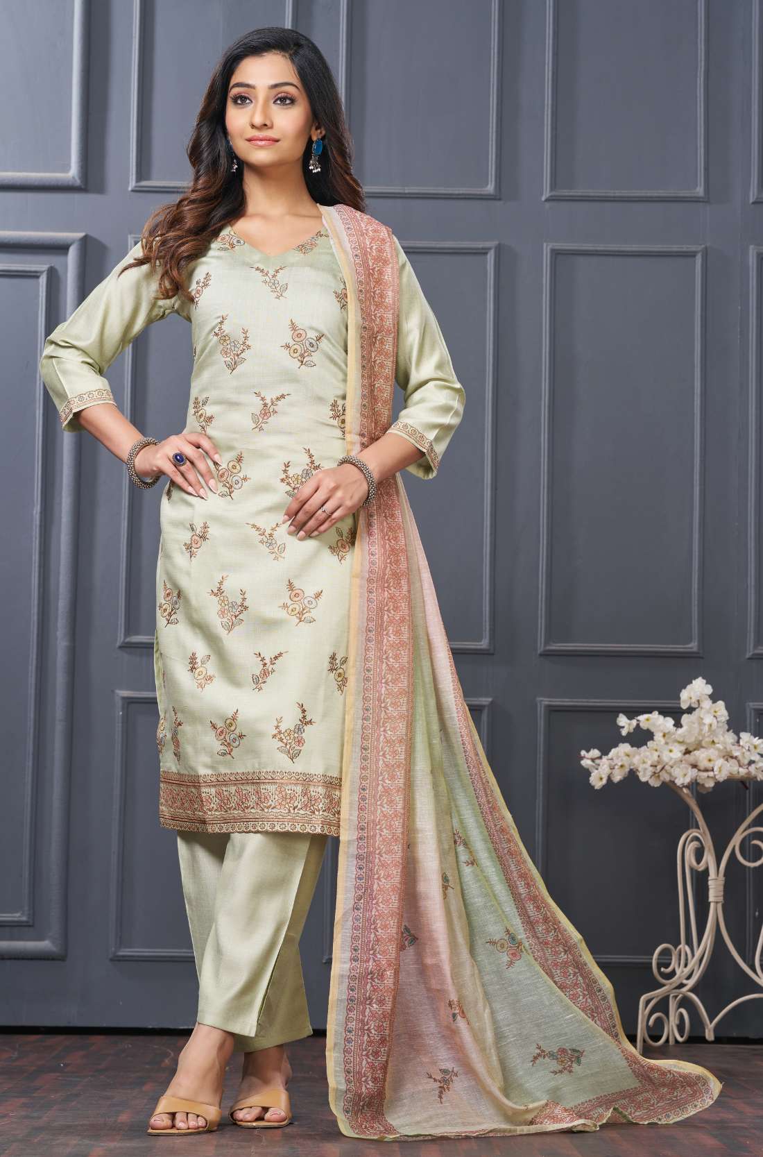 Front full-length view of a model showcasing the mint green silk 3-piece variant, featuring delicate gold embroidery details on the neckline, paired with straight trousers and a matching green scalloped border dupatta.