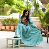 Model sitting in sea green aari embroidery flared kurti with contrast black yoke