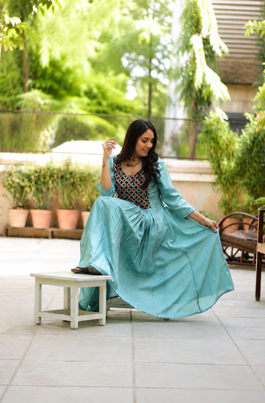Model sitting in sea green aari embroidery flared kurti with contrast black yoke