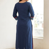 Back view of a model standing indoors, wearing a solid dark blue straight kurta and matching pants.