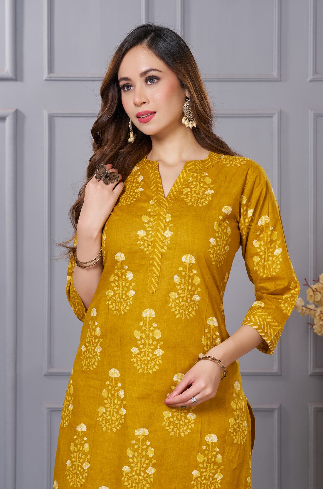 Close up view of the V neckline design showcasing white lace inserts and contrasting border details on the ochre yellow floral printed cotton kurta