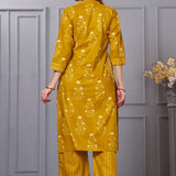 Back view of the ochre yellow straight fit floral cotton kurta set showcasing the fit of the trousers and the falling pattern of the printed dupatta