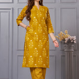 Side profile view of a model in the ochre yellow floral printed cotton kurta set showcasing the elegant side pockets and chevron trousers