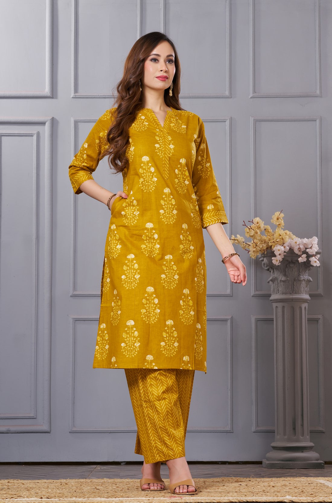 Side profile view of a model in the ochre yellow floral printed cotton kurta set showcasing the elegant side pockets and chevron trousers