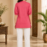Full-length back view of a woman wearing the dark peach rayon top with white trousers.