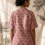 Back profile of a women's blush pink hand block print cotton shirt with short sleeves and curved hem.
