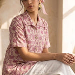 Front view of a women's blush pink floral hand block print cotton shirt with wooden buttons and short sleeves.