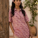 Women's blush pink floral hand block print cotton shirt styled casually while seated at an outdoor café.