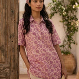 Women's blush pink floral hand block print cotton shirt styled casually while seated at an outdoor café.