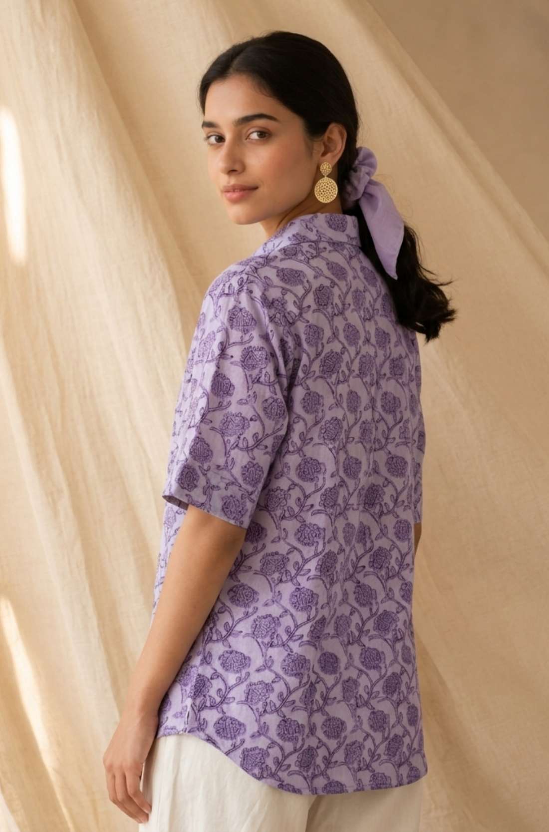 Back view of a women's lavender floral block print cotton shirt with short sleeves and curved hem.