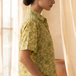 Side profile of a women's yellow floral block print cotton shirt with relaxed fit and collared neckline.