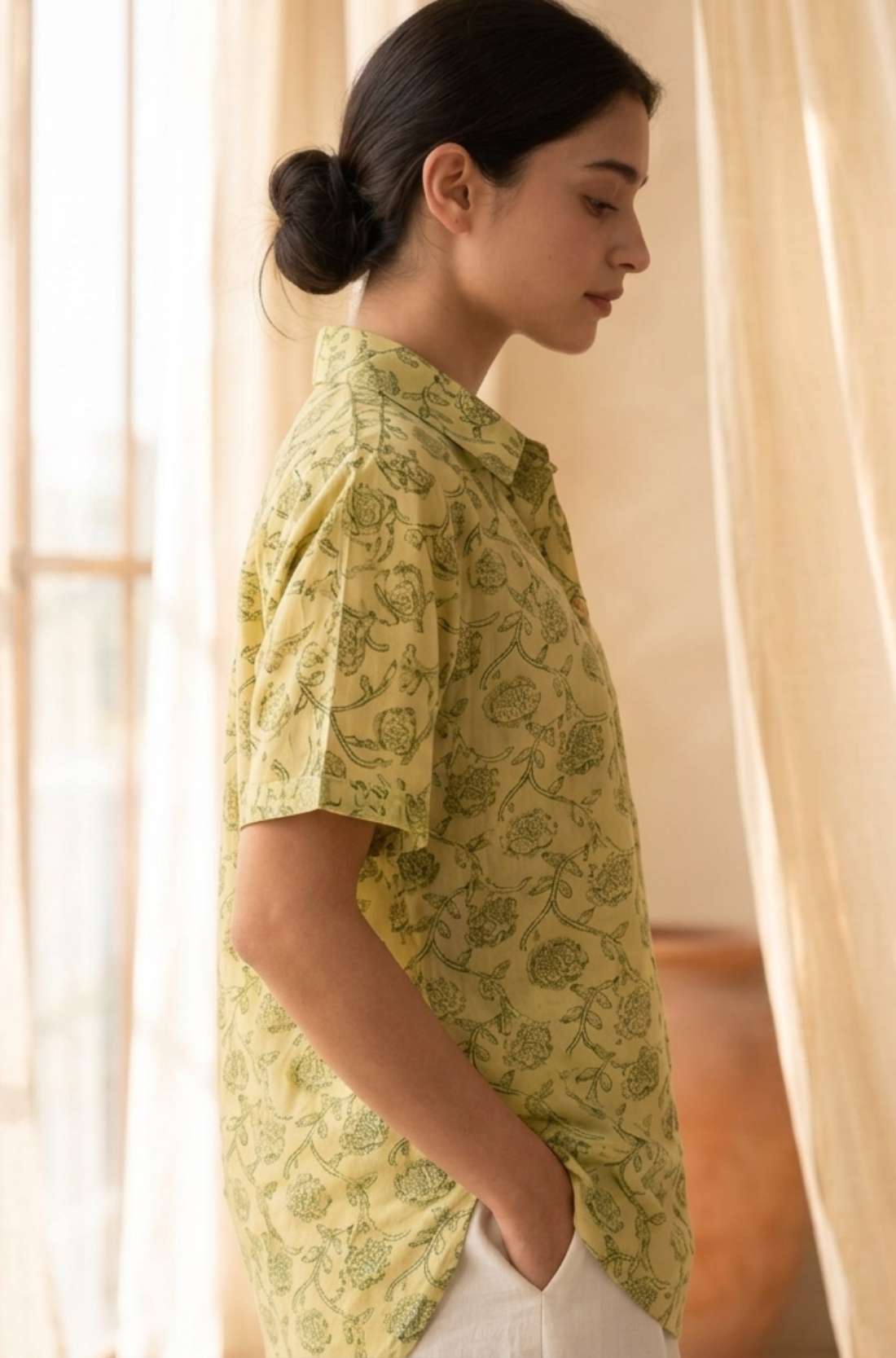 Side profile of a women's yellow floral block print cotton shirt with relaxed fit and collared neckline.