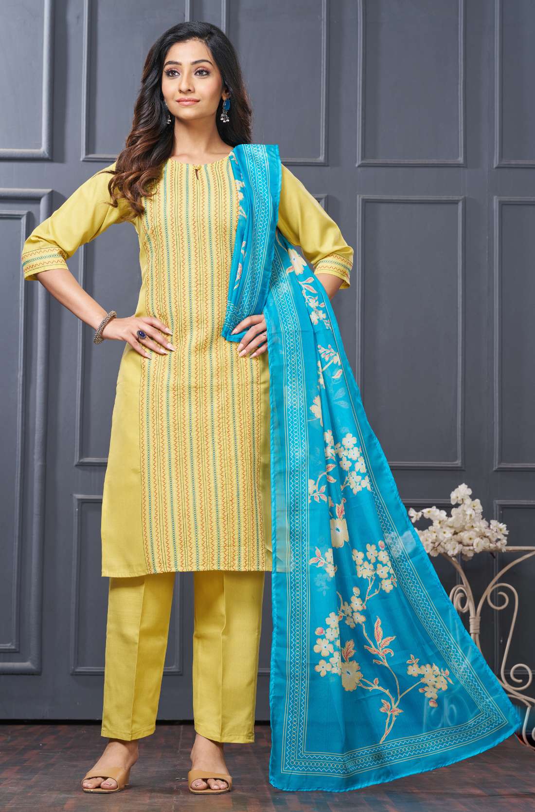 Profile view of a model in a yellow cotton ethnic suit set displaying the straight-cut pants silhouette and the beautiful pattern of the draped matching dupatta