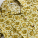 Flat lay of a yellow hand block print cotton shirt featuring floral print, collar, and wooden button placket.
